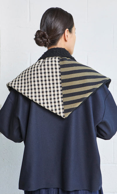 Plümo- Person with dark hair in a low bun wears a navy jacket featuring the handcrafted Gingham Patch Scarf collar.
