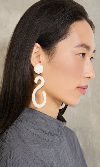 Plümo- Woman in gray top models large Horn Clip-On Earrings, facing left against a neutral background.