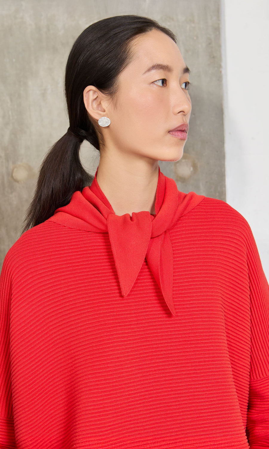 Plümo- Woman with long dark hair wears the Jona Necktie - Lava top and silver earrings.