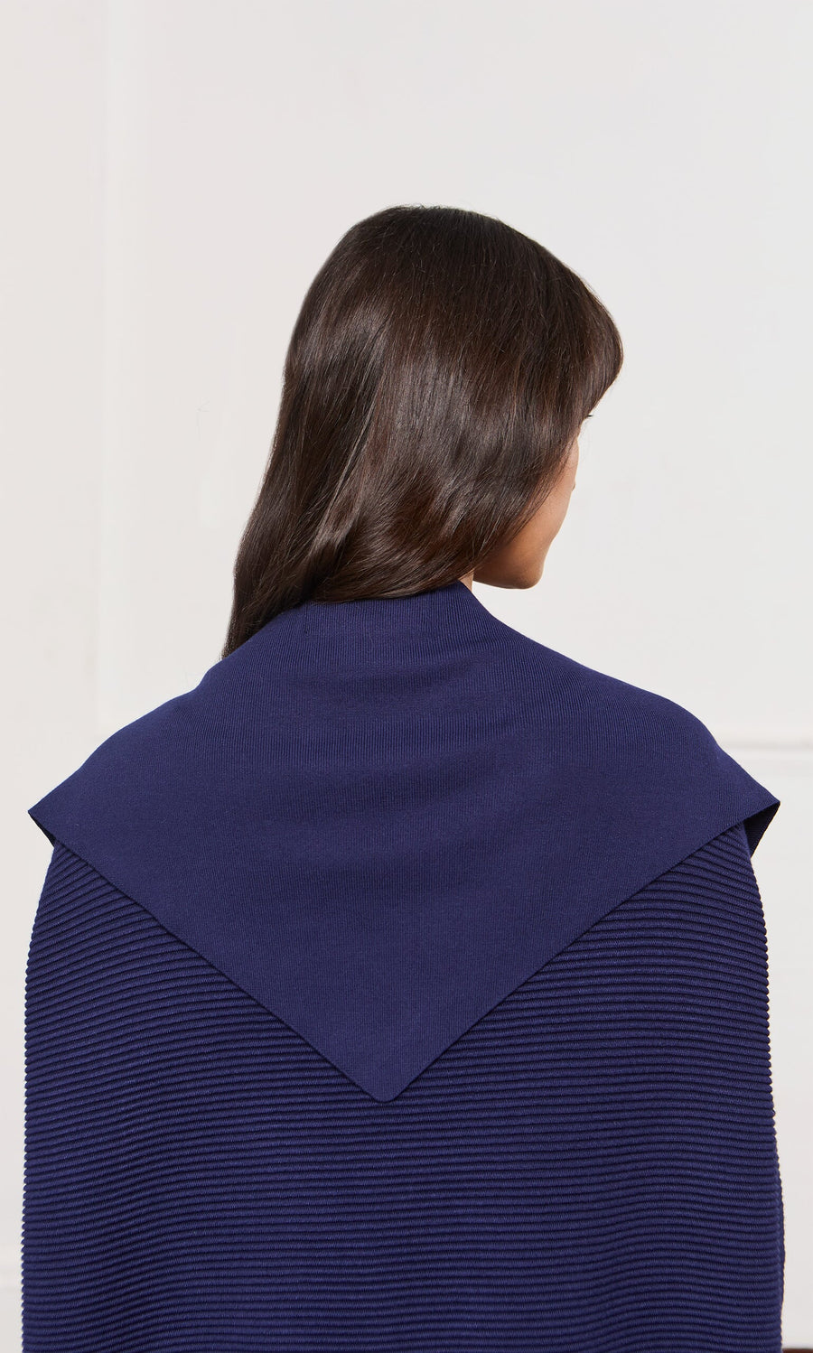 Plümo- A person with long dark hair wears a navy Jona Necktie featuring a distinctive triangular collar.