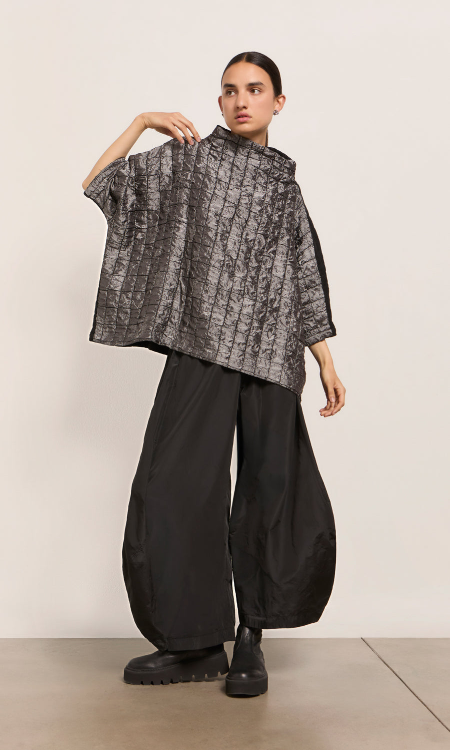 Plümo  Person in a loose gray top and black Hooley Pants stands against a plain background.