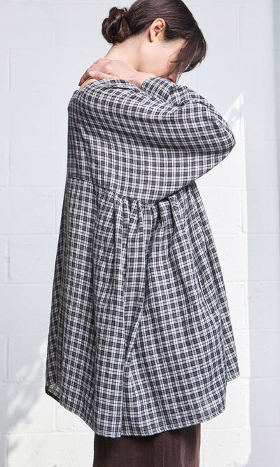 Plümo- Model wears the Kelli Blouse - Plaid, standing sideways with head down and hands resting on their shoulders.