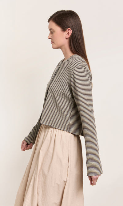 Plümo  Woman in a Lavelle Top and beige skirt stands in profile, showcasing eco-friendly materials and fair production.