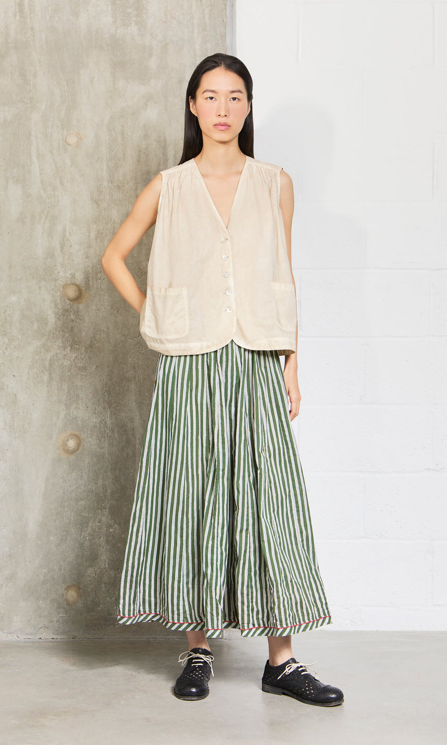 Plümo- Woman wearing a beige sleeveless top and the Lilia Skirt, a green-and-white striped cotton skirt with elastic waist.