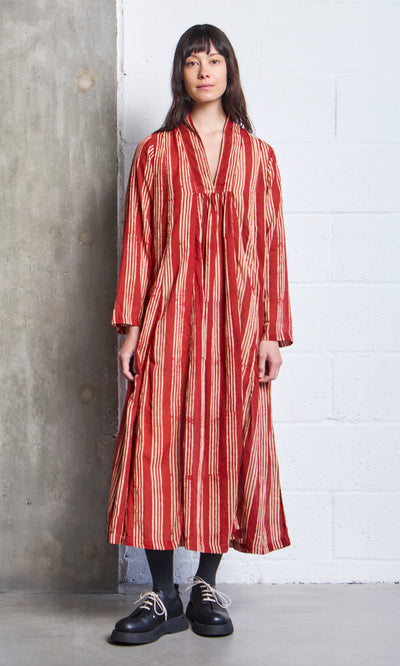 Plümo- Woman wearing the Lina Stripe Dress, a long, loose block-printed A-line with vertical cream stripes, standing indoors.