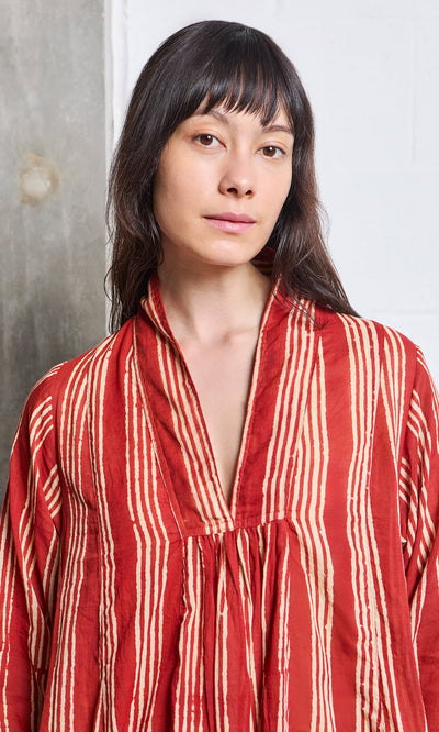 Plümo- Woman with long dark hair wearing the Lina Stripe Dress, standing indoors against a neutral background.