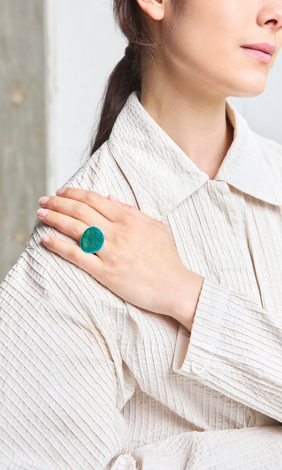 Plümo- Woman in a textured white shirt wears the handmade Lowen Ring, Eco-Silver jewellery from Cornwall, on her shoulder.