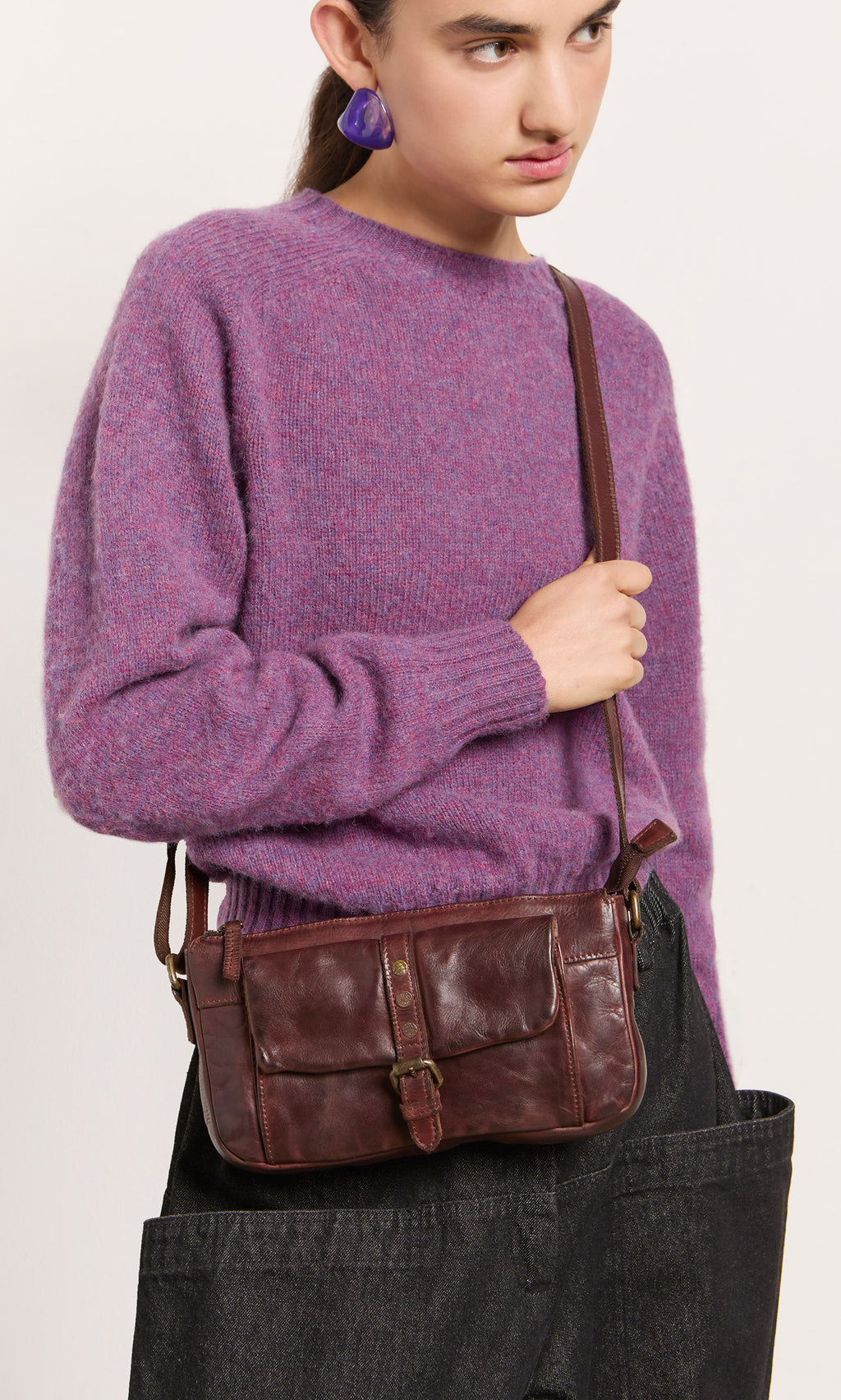 Plümo  Person in a fuzzy purple sweater, black pants, with the Luxton Bag slung stylishly over one shoulder.