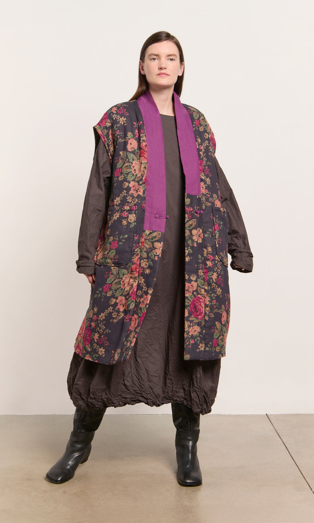 Plümo  Person wears a long brown dress, black boots, and the Manton Gilet against a plain background.