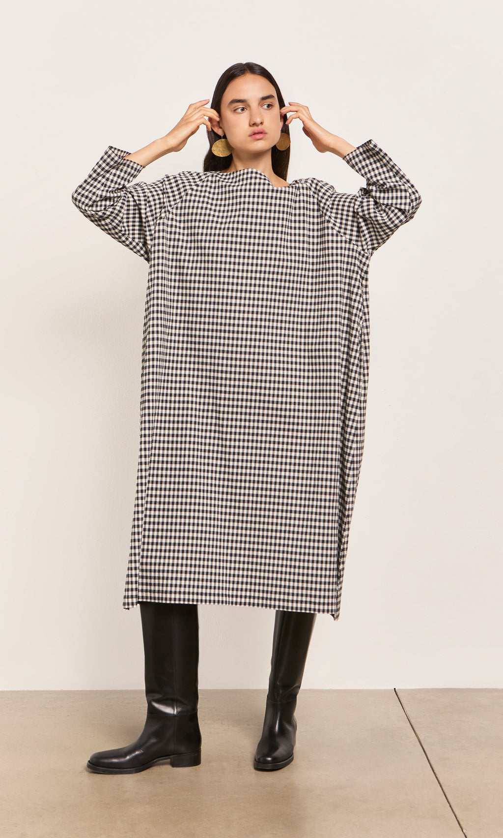 Plümo  Person in a Marsell Dress - Gingham, designed in London, pairs it with black knee-high boots.