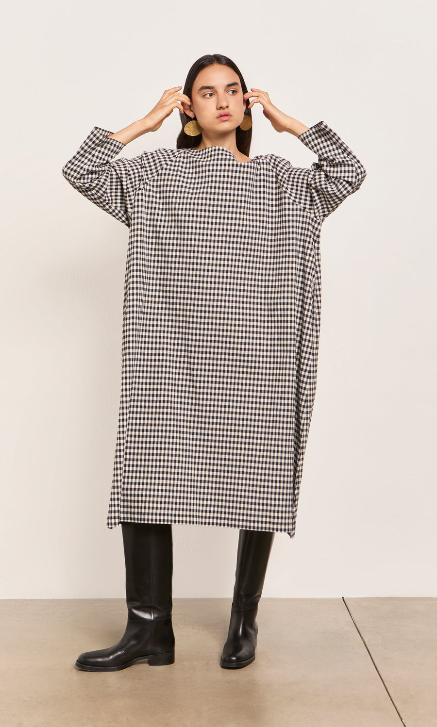 Plümo  Person in a Marsell Dress - Gingham, designed in London, pairs it with black knee-high boots.