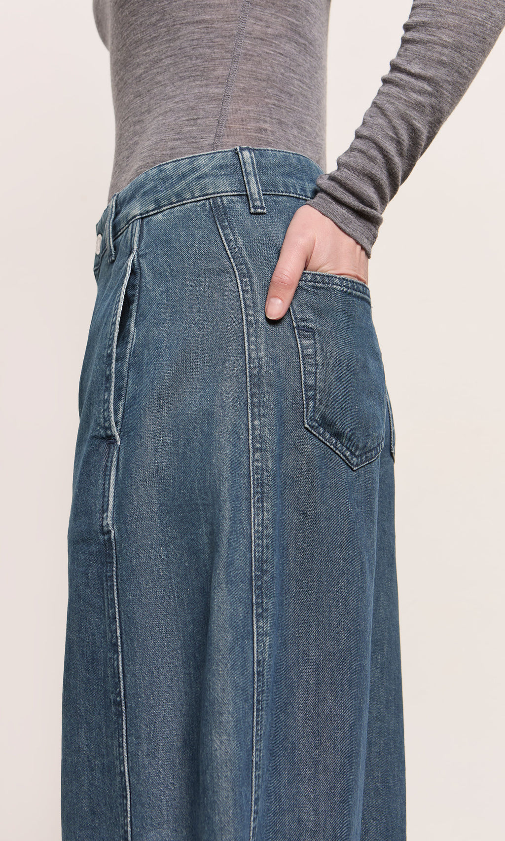 Plümo  A person in a gray long-sleeve shirt and Maud Barrel Pants with one hand in the back pocket.