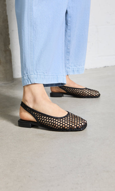 Plümo- Person wearing Noa Slingbacks and light blue pants, inspired by Danish design, standing on a concrete floor.