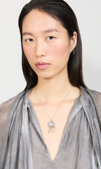 Plümo- A woman in a sheer gray top wears the Pearled Necklace, looking directly at the camera.