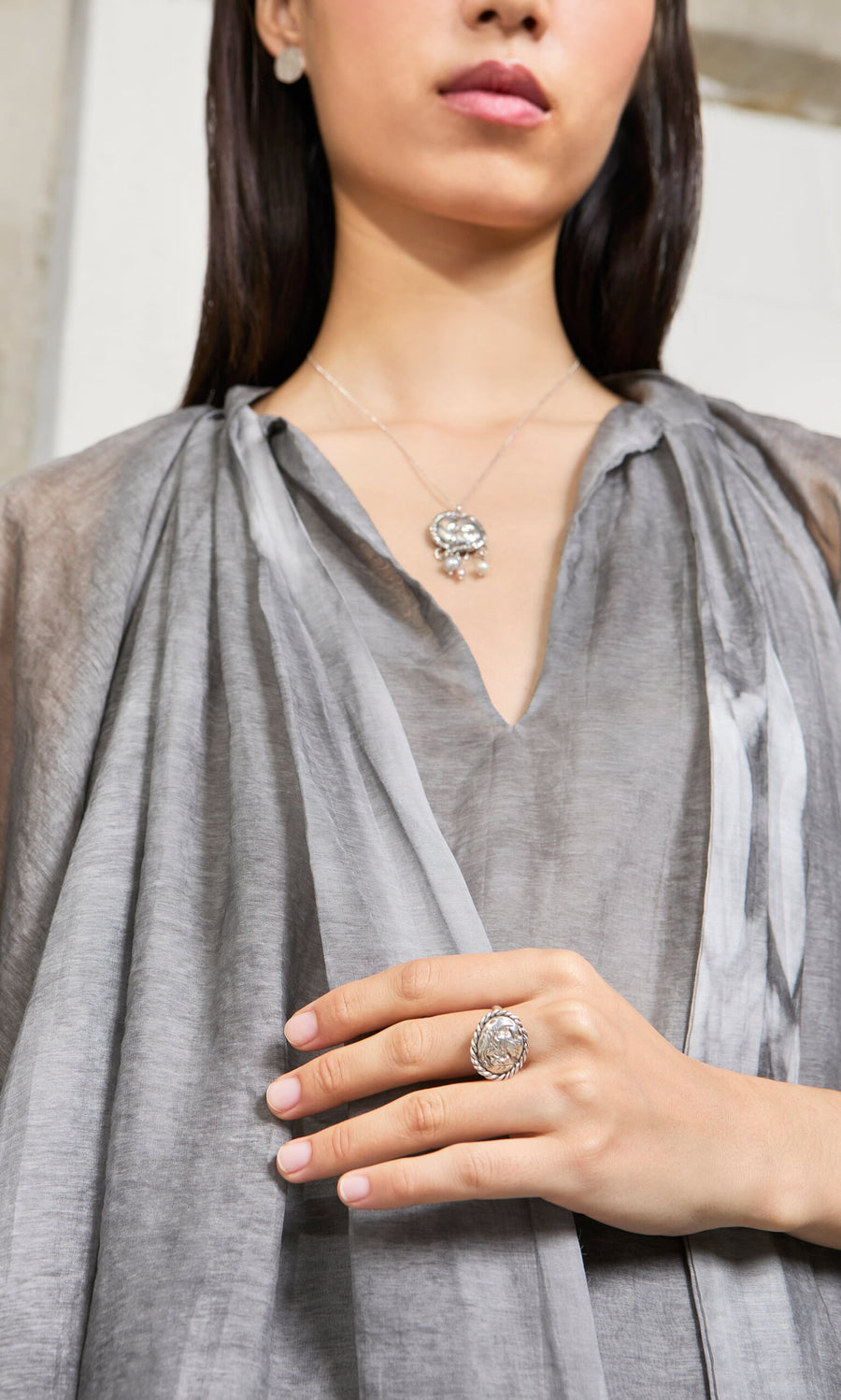 Plümo- Woman wearing a sheer gray top and the Pearled Necklace with a large silver ring.