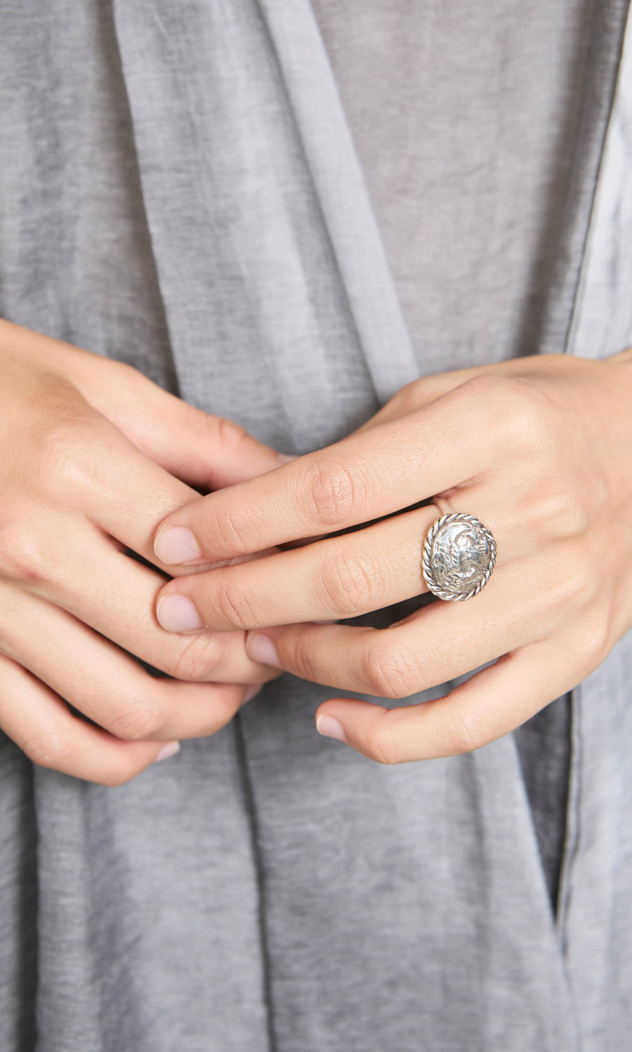 Plümo- Close-up of hands wearing the Silver Wild Ring, a handcrafted sterling silver piece with a clear gemstone.