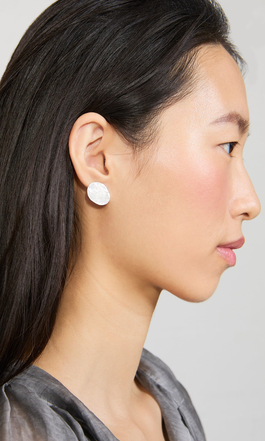Plümo- Woman in profile wearing Noreen Studs, with straight dark hair and a light gray top, facing right.