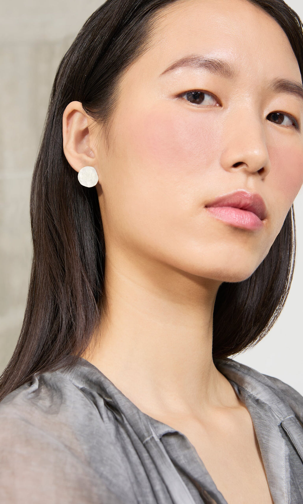 Plümo- A woman with straight dark hair wears Noreen Studs and a gray blouse, looking confidently at the camera.