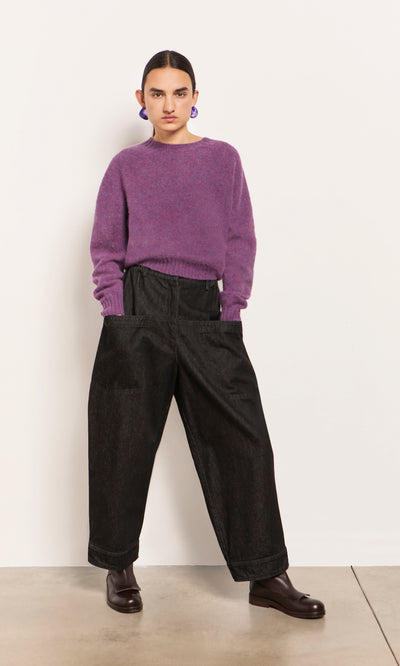 Plümo  Woman in a purple sweater, Polder Pants - Washed Black, and brown boots stands by a white wall.