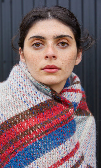 Plümo  A person with freckles wearing a multi-colored Random Throw.