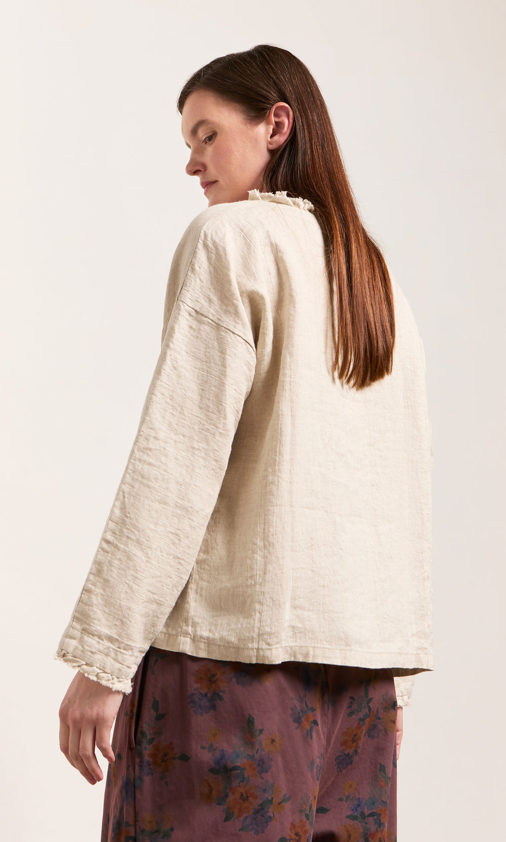 Plümo  A woman in an Ella Ruffle Top with a relaxed silhouette and floral pants stands facing away, looking over her shoulder.