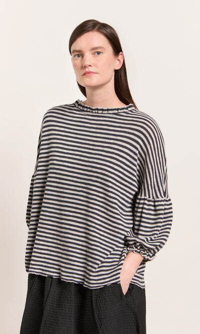 Plümo  Woman in a Danish-design, OEKO-TEX certified Dawn Grey Ruffle Top with ruffled collar and textured skirt.