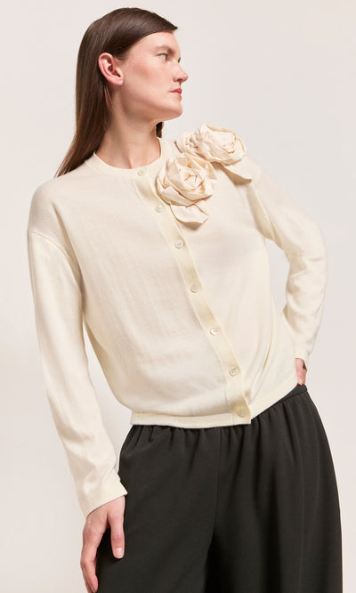 Plümo  Model in Sugared Corsage Cardigan in ecru with sculpted shoulder details and black pants, gazing to the side.