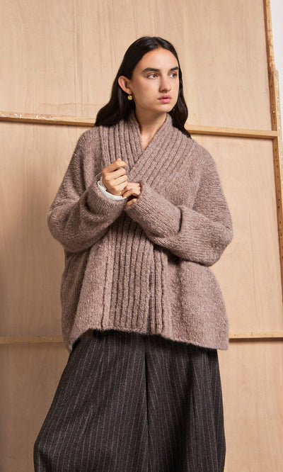 Plümo  A person wears a Shawl Collar Jumper with wide pinstripe pants, standing in front of a wooden panel backdrop.