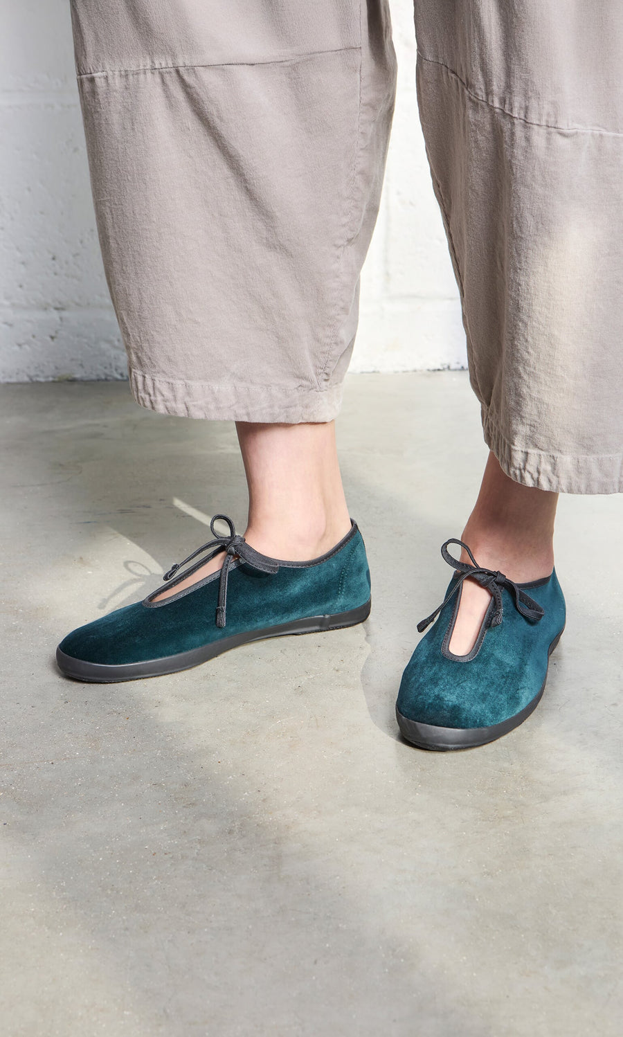 Plümo- Person wearing teal Velvet Prim Ballerinas and light gray wide-leg pants, standing on a concrete floor.