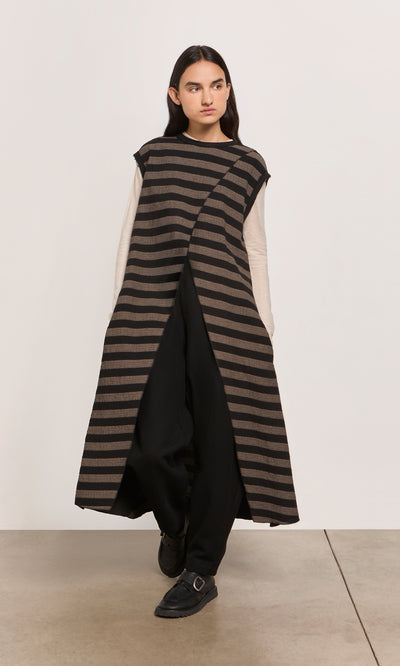 Plümo  Person wearing the Venlo Stripe Tunic over a beige top and black pants, standing indoors.