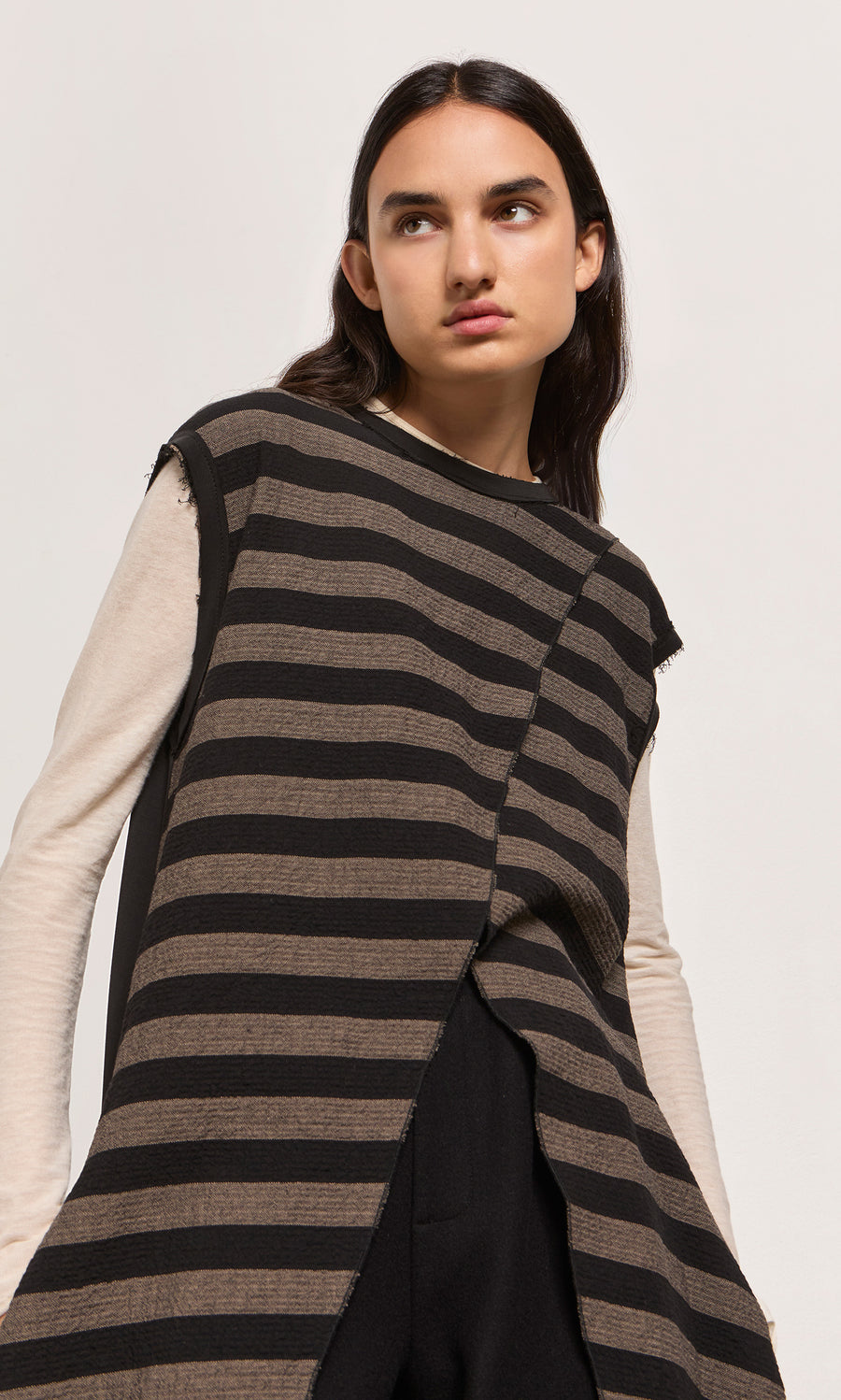 Plümo  Woman in the Venlo Stripe Tunic layered over a long-sleeve beige shirt, looking to the side.