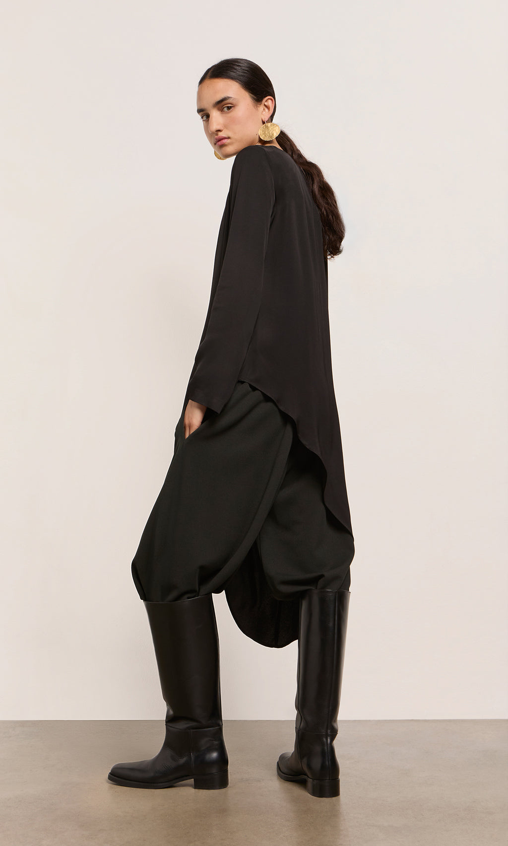 Plümo  Woman in the Vermeer Top, wide black pants, and knee-high boots—matt-satin crepe, made in Italy.