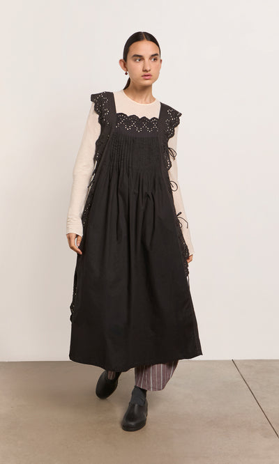 Plümo  Woman in a Vintage Lace Dress over a cream top and striped pants, standing on a light floor.