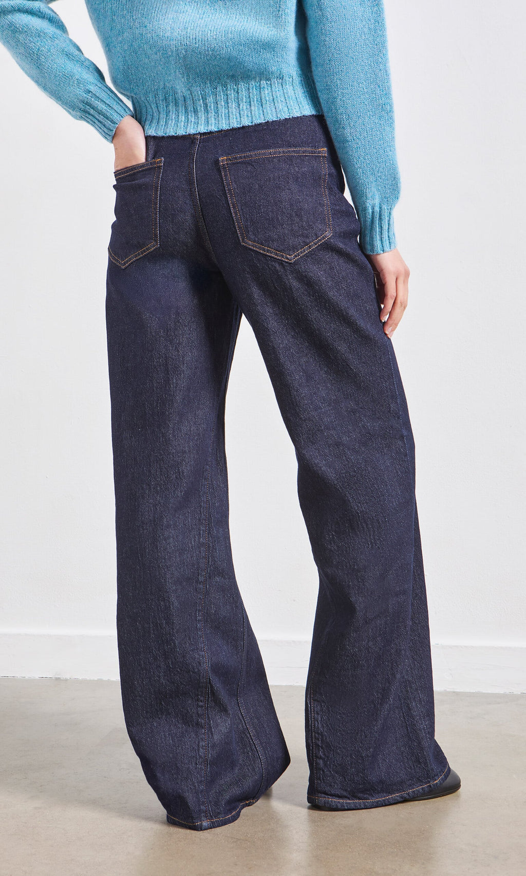 Plümo- Person wearing Belted Wide Jeans and a light blue sweater, hand in their back pocket.