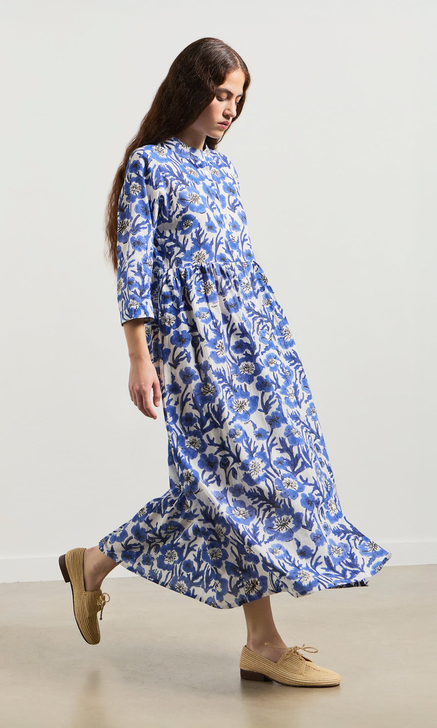 Plümo- Woman in a Blue Pansy Dress walks indoors, wearing tan lace-up shoes.