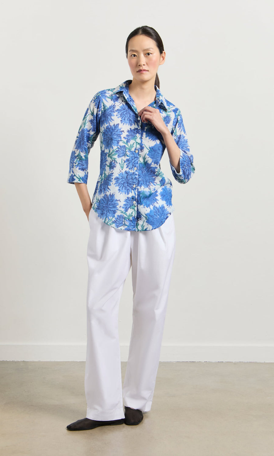 Plümo- Person wearing the Blue Thistle Shirt with shell buttons and white pants, standing against a light background.