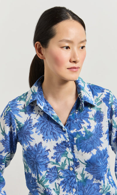 Plümo- Woman with dark hair in a ponytail wears the Blue Thistle Shirt, looking to the side.