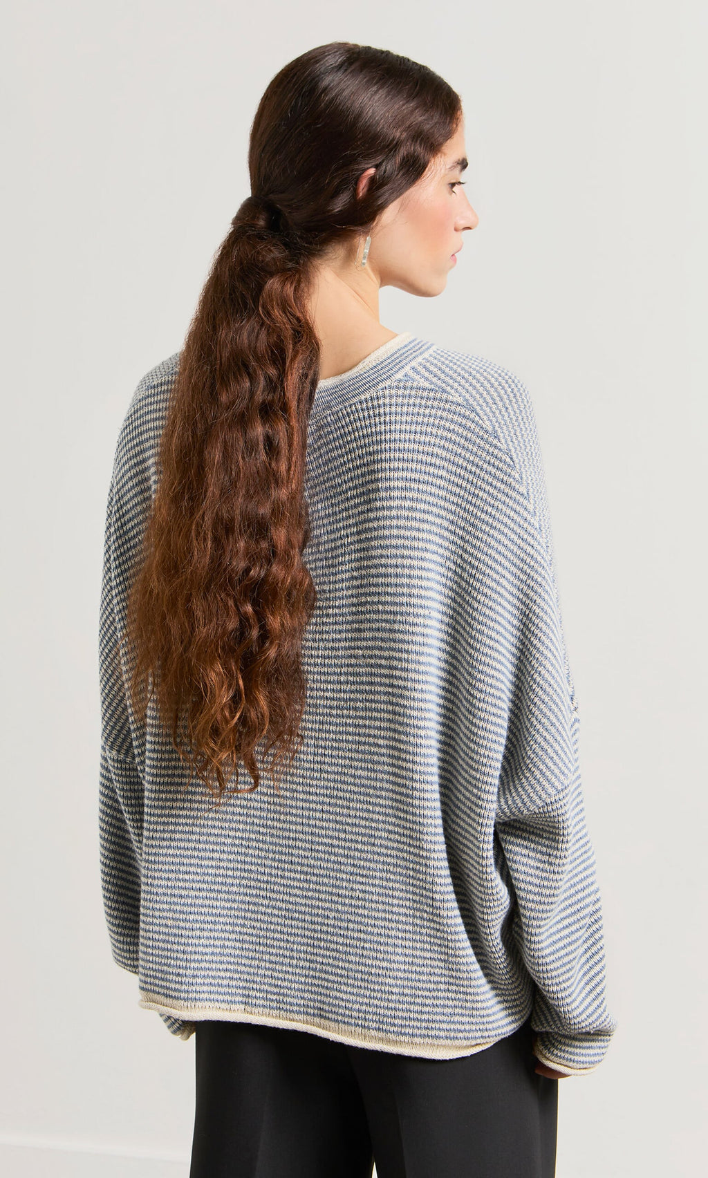 Plümo- A woman with long wavy hair in a low ponytail wears the relaxed fit Boathouse Jumper, facing away.