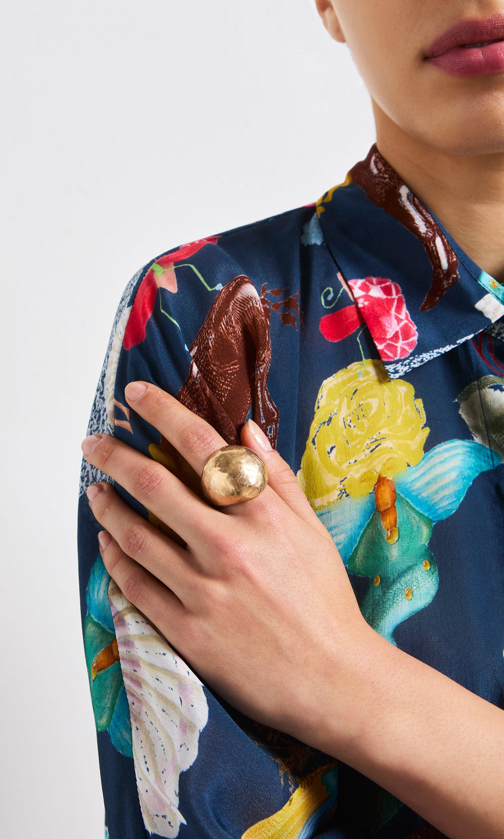 Plümo- Person wearing a colorful floral shirt and the handcrafted Bolla Ring, hand resting on their shoulder.