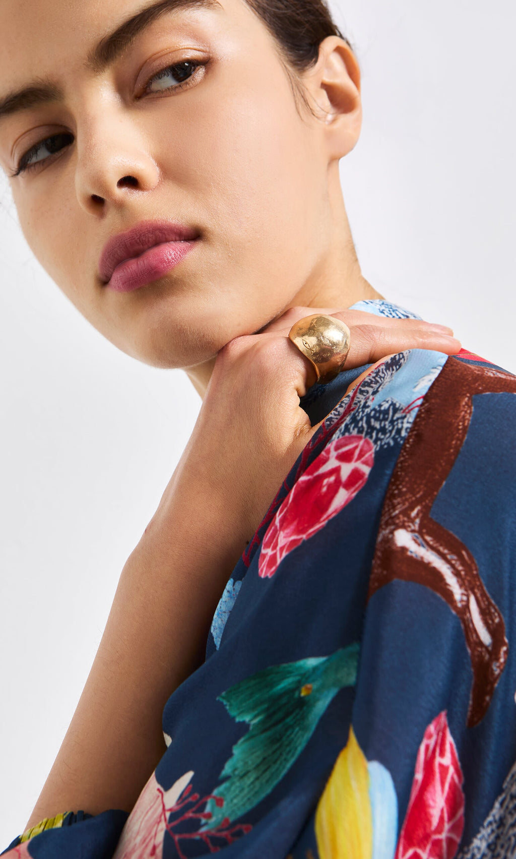 Plümo- Woman in a blue floral top wears the Bolla Ring, a bronze statement piece crafted using lost wax casting.