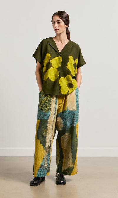 Plümo- Woman in a floral top and Brushstroke Pants featuring an impressionist print, drawstring waist, and pockets.