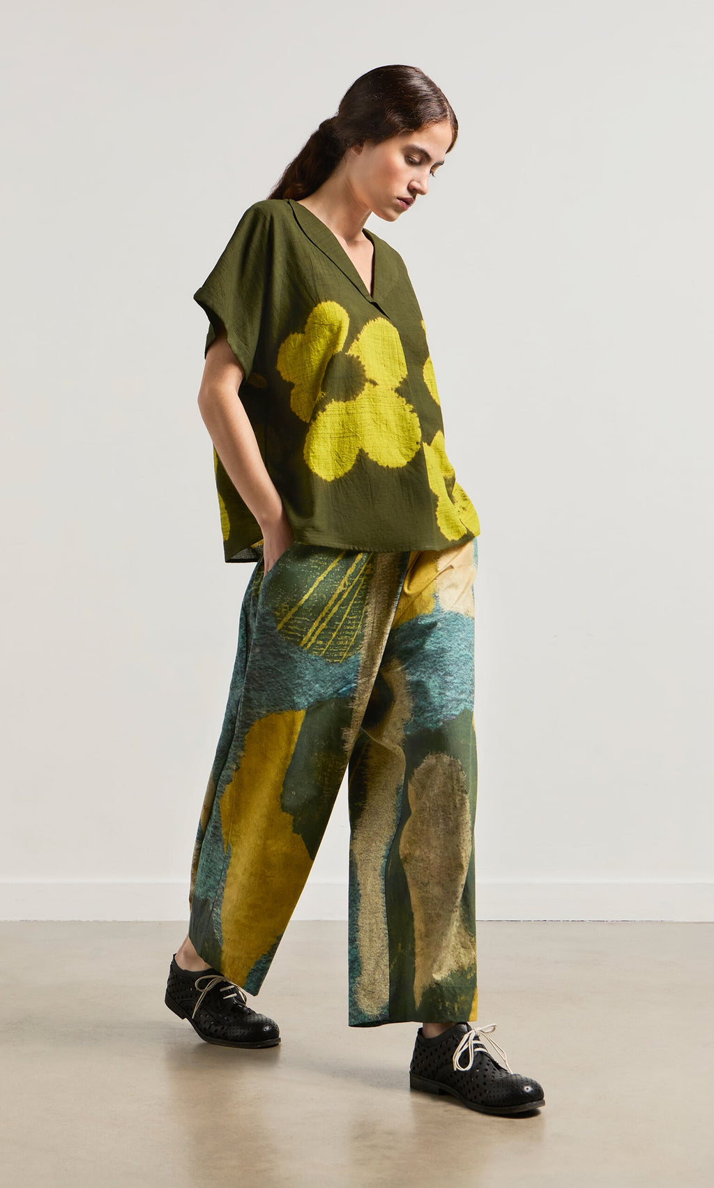 Plümo- Woman in a loose green top and Brushstroke Pants featuring an impressionist print and drawstring waist.