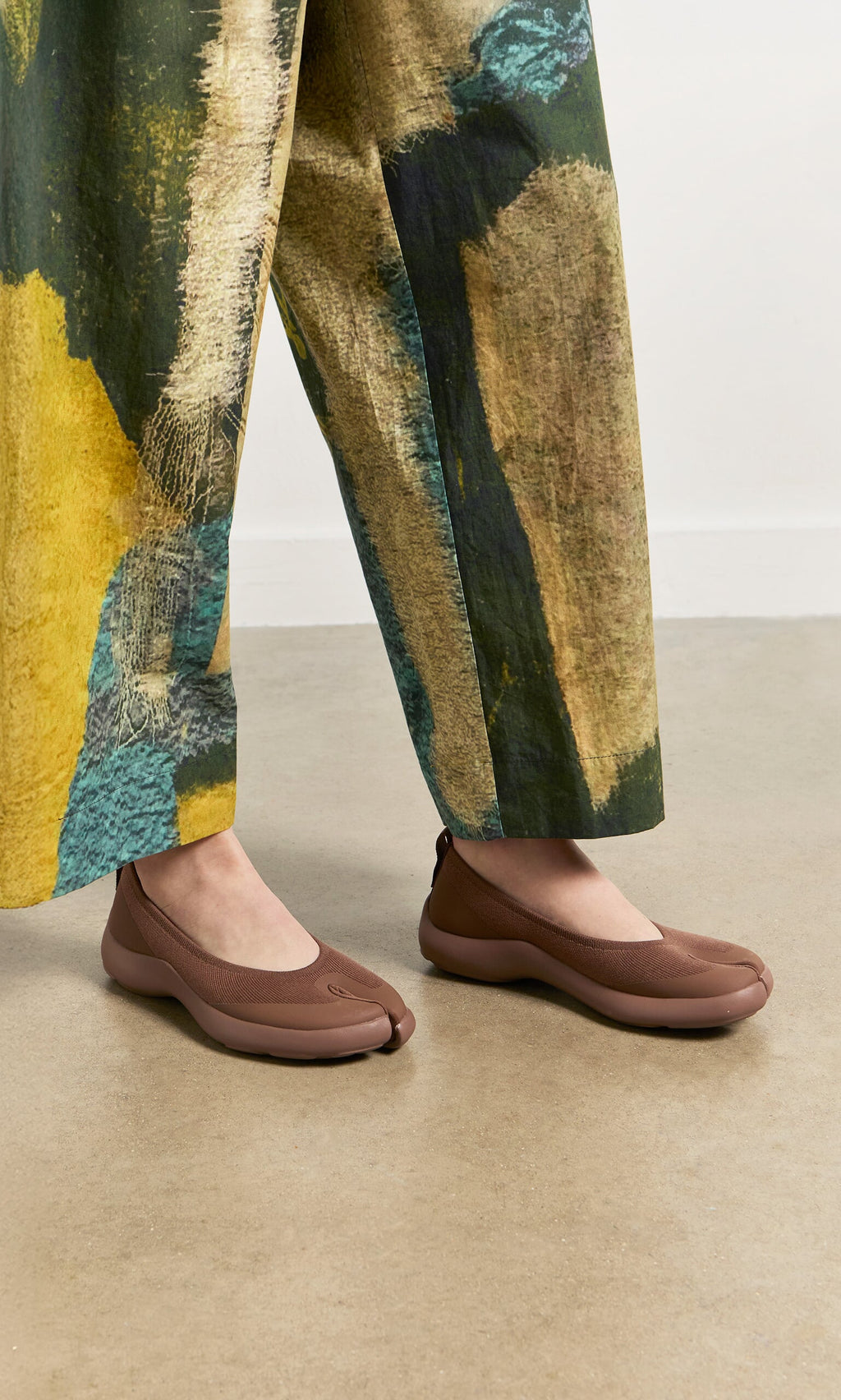 Plümo- Wearing wide-leg, abstract pants and Choco Tabi Ballerinas on a light-colored floor.
