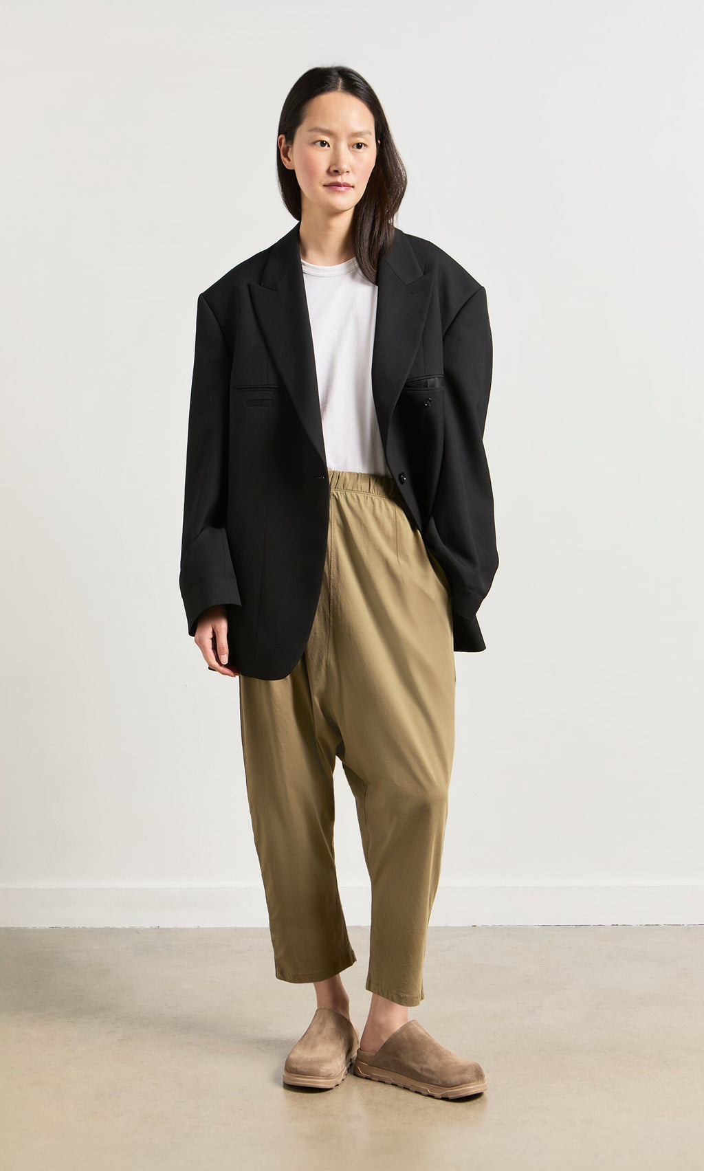 Plümo- A woman in Como Mules with a comfy moulded footbed stands against a plain background in chic, minimalist style.