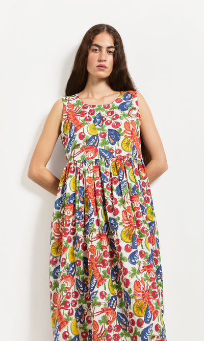 Plümo- Woman in the Corallo Dress, a sleeveless hand-printed cotton voile with colorful floral and leaf patterns.