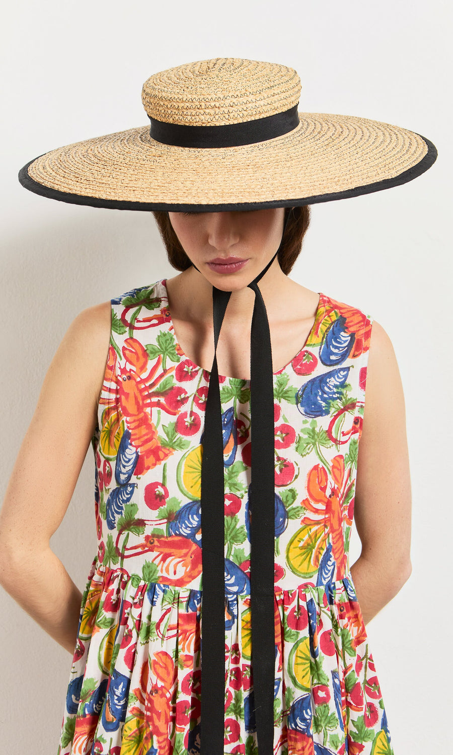 Plümo- Woman in the Corallo Dress, a colorful hand-printed cotton voile with shell buttons and a wide-brimmed straw hat.
