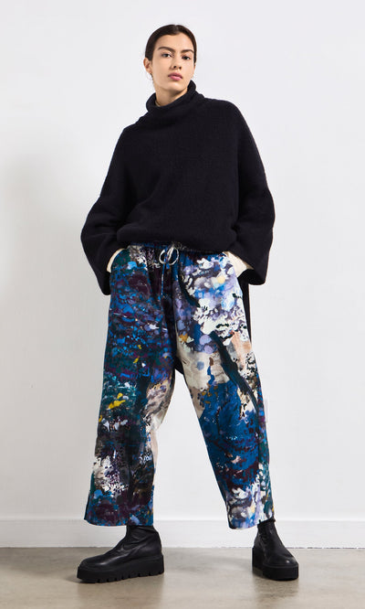 Plümo- Woman in a black turtleneck, Covey Pants with elastic waist, and black platform boots.