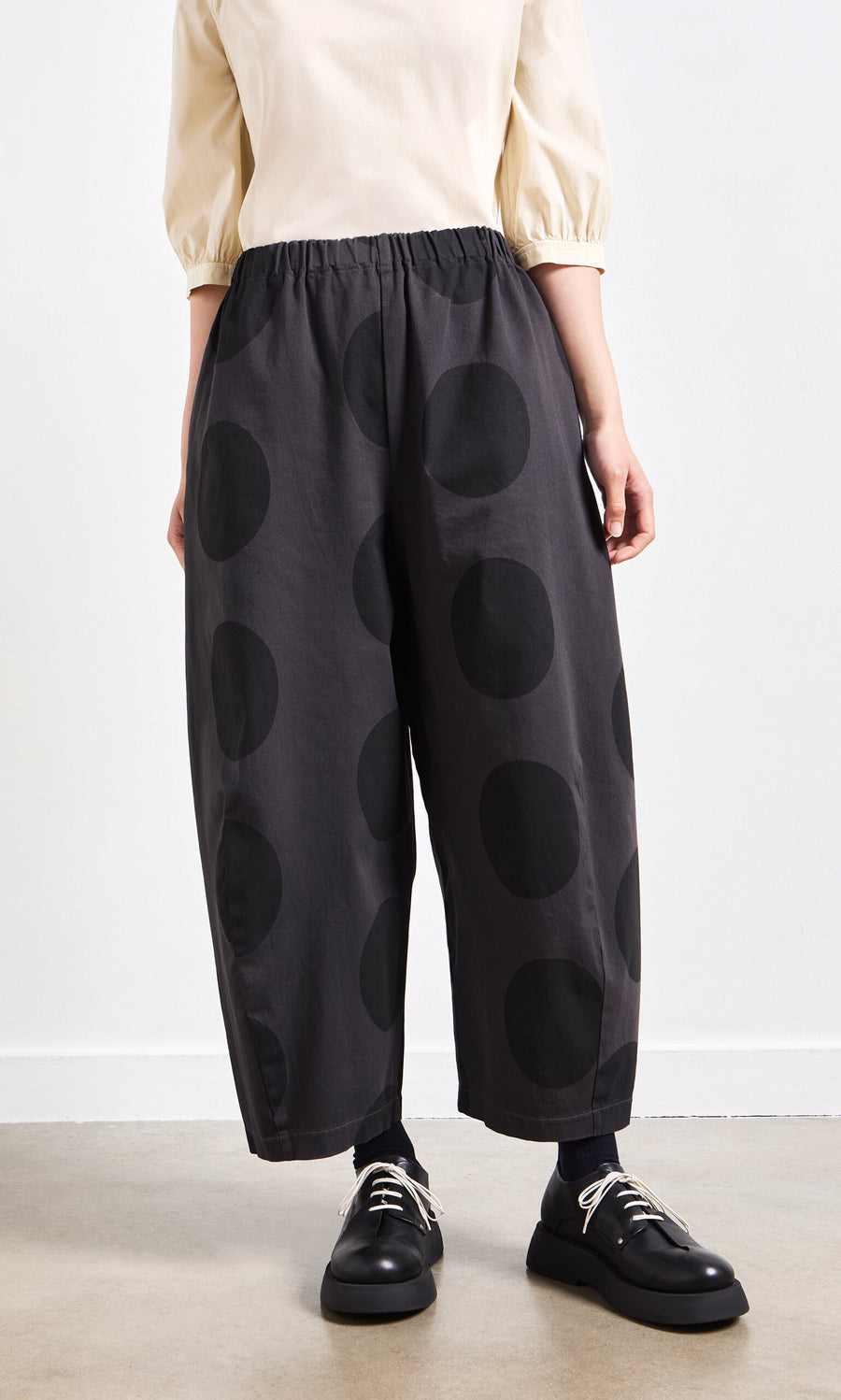 Plümo- Person wearing Easy Point Pants with large black polka dots, black shoes, and a cream top.