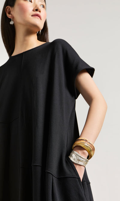 Plümo- Woman in a loose black dress, stacked bangles, natural horn earrings, and the Ember Cuff bracelet, looking to the side.
