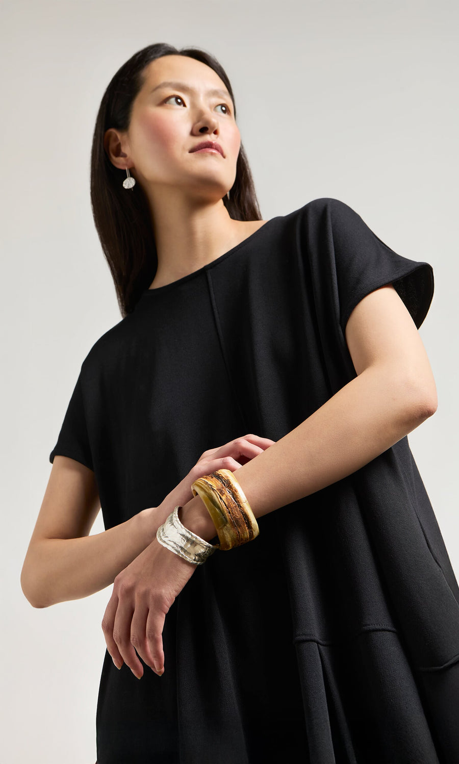 Plümo- Woman in a black dress wears the Ember Cuff bracelet, posed against a light gray background.